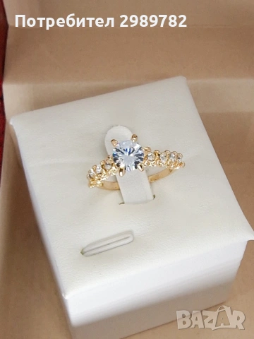  Класически дамски пръстен с централен прозрачен камък и коронна рамка.