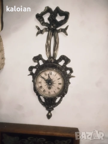 Стар механичен стенен часовник. Навива се с ключе, работи. Доста е безшумен. Изцяло е от бял бронз с