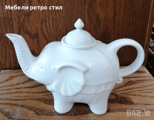 Чайник от бял порцелан, изработен във формата на щастливо слонче с вдигнат хобот и релефни детайли. 