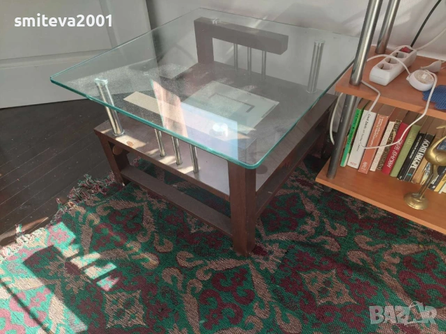 Атрактивна дървена и стъклена холна маса с метални елементи.